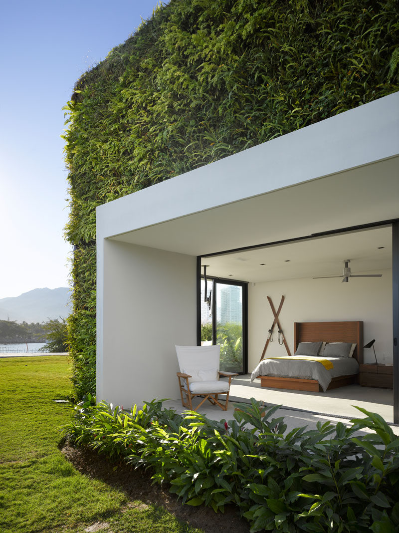 This modern bedroom has a covered outdoor space, while a green wall has been installed on the exterior of the house. #GreenWall #ModernBedroom #Architecture