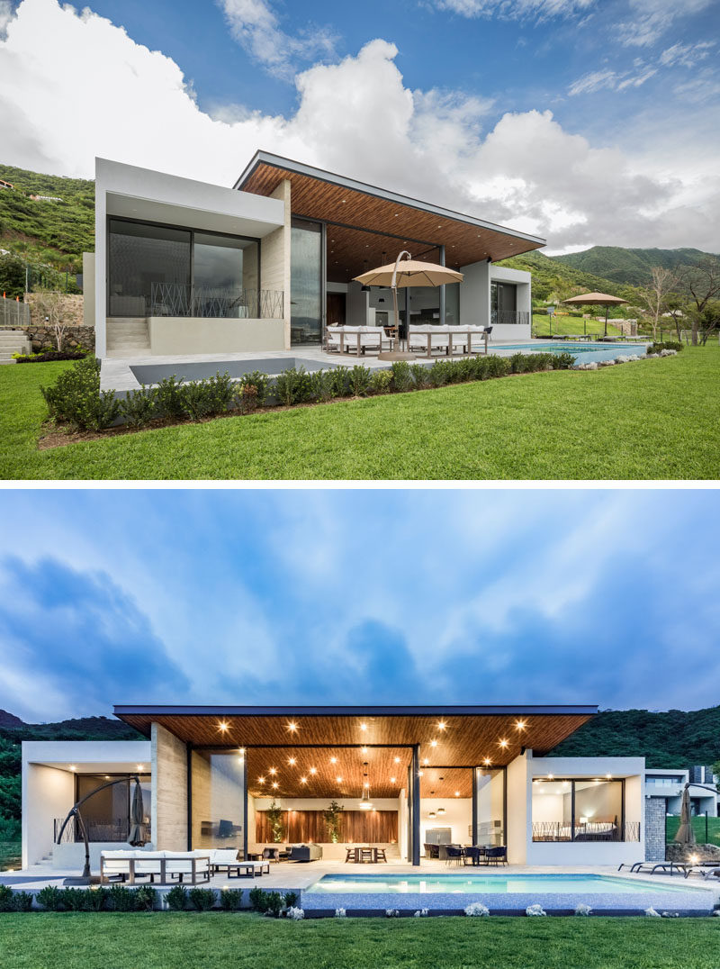 This modern house opens up to a backyard with a sunken firepit, an outdoor lounge with an umbrella, a swimming pool and a landscaped lawn. Located under the roof overhang is an outdoor dining area too. #Backyard #SunkenFirepit #SwimmingPool #ModernHouse