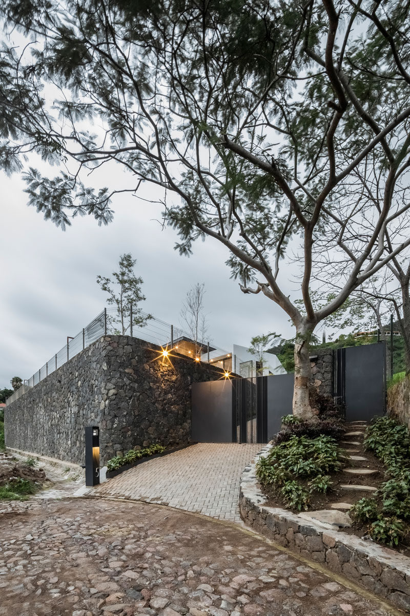 This modern house has a large stone wall at that follows the driveway up to the house. #ModernHouse #StoneWall #Driveway