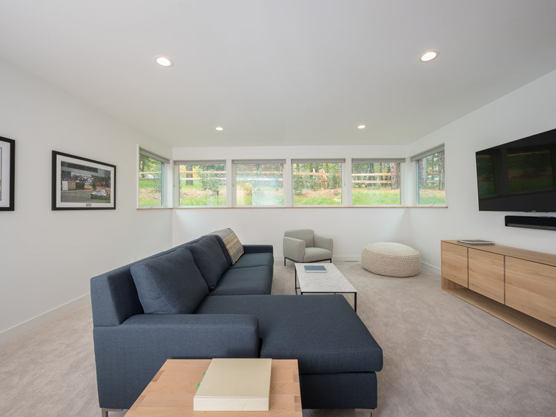 In this minimalist media room, a large couch is focused on the television, perfect for movie watching, while window allow some natural light into the space. #MediaRoom #InteriorDesign #Windows