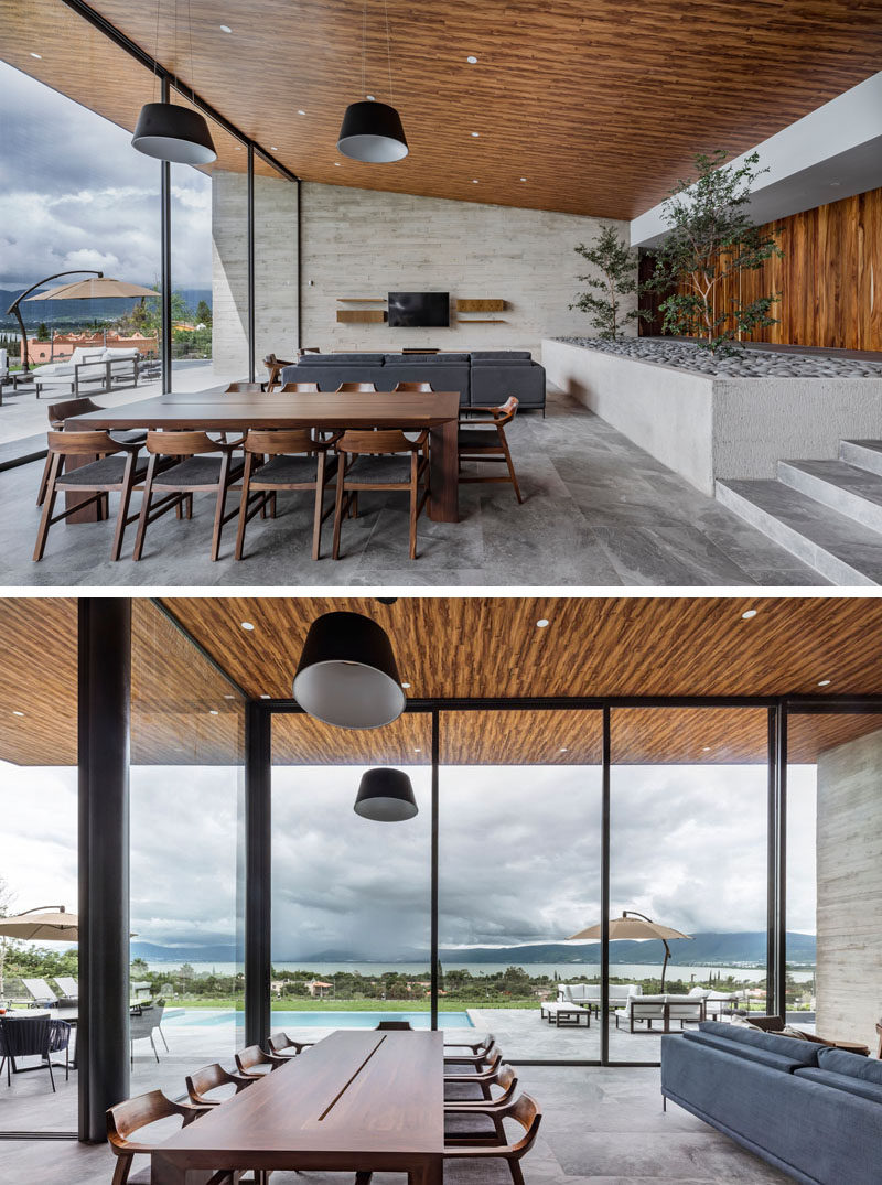 The living room and dining room in this modern house share the open space and look out to the backyard and views through large sliding glass walls. #SlidingGlassWalls #ModernDiningRoom #WoodCeiling