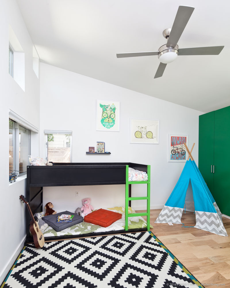 In this kid's bedroom, a high sloped ceiling creates a sense of openness and allows for a raised bed to be included. #KidsBedroom #BedroomDesign