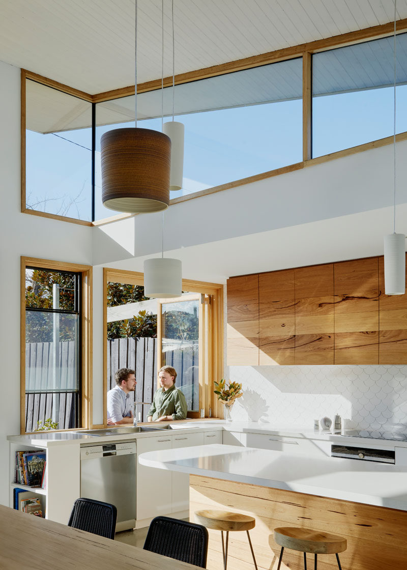 A large window in the kitchen opens up to the recycled brick patio outside and acts as a bar. #Windows #KitchenDesign #ModernKitchen