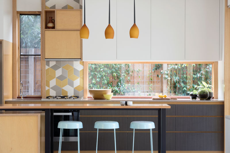 In this modern kitchen, windows have been used as a backsplash, plus they allow natural light and a view of the garden, while a small section of colorful tiles adds a playful touch. #ModernKitchen #Windows #KitchenWindow #KitchenDesign