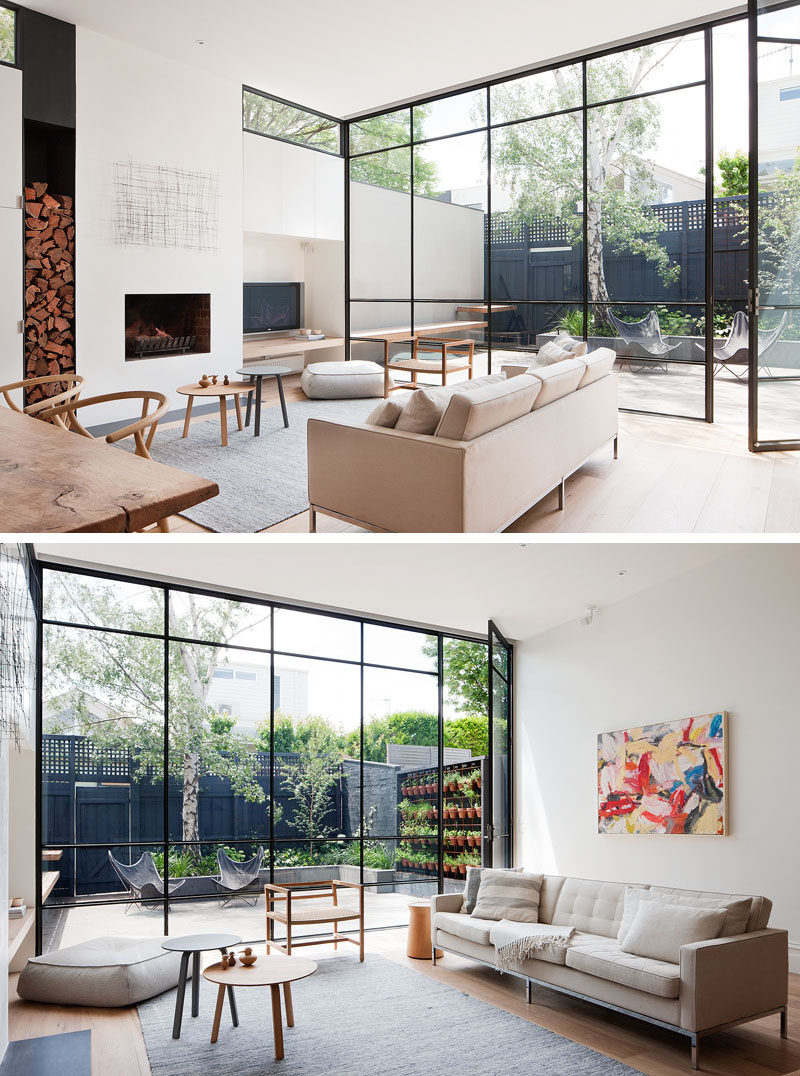 This modern living room has large floor-to-ceiling black framed windows (and a door) that flood the room with natural light and provide a view of the courtyard. #ModernLivingRoom #Fireplace #BlackFramedWindows #Windows