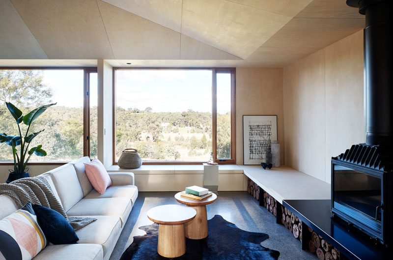 A purpose-built, low-set bench seat that runs around the this living room, creating a space for guests and inhabitants to have casual, comfortable sit-downs. #Bench #LivingRoom #Windows #BlackFireplace