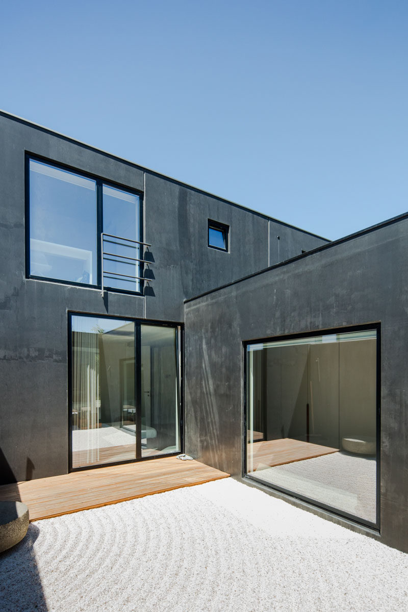 This small and private courtyard off the master bedroom has a small wood patio area and the rest is covered in rippled sand. #ModernHouseDesign #Courtyard #Windows