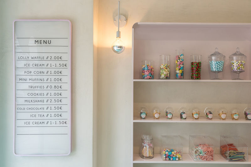 Soft pastel pink outlines the menu board in this small sweet store and provides a backdrop for some shelving displays. #PastelPink #RetailDesign #InteriorDesign
