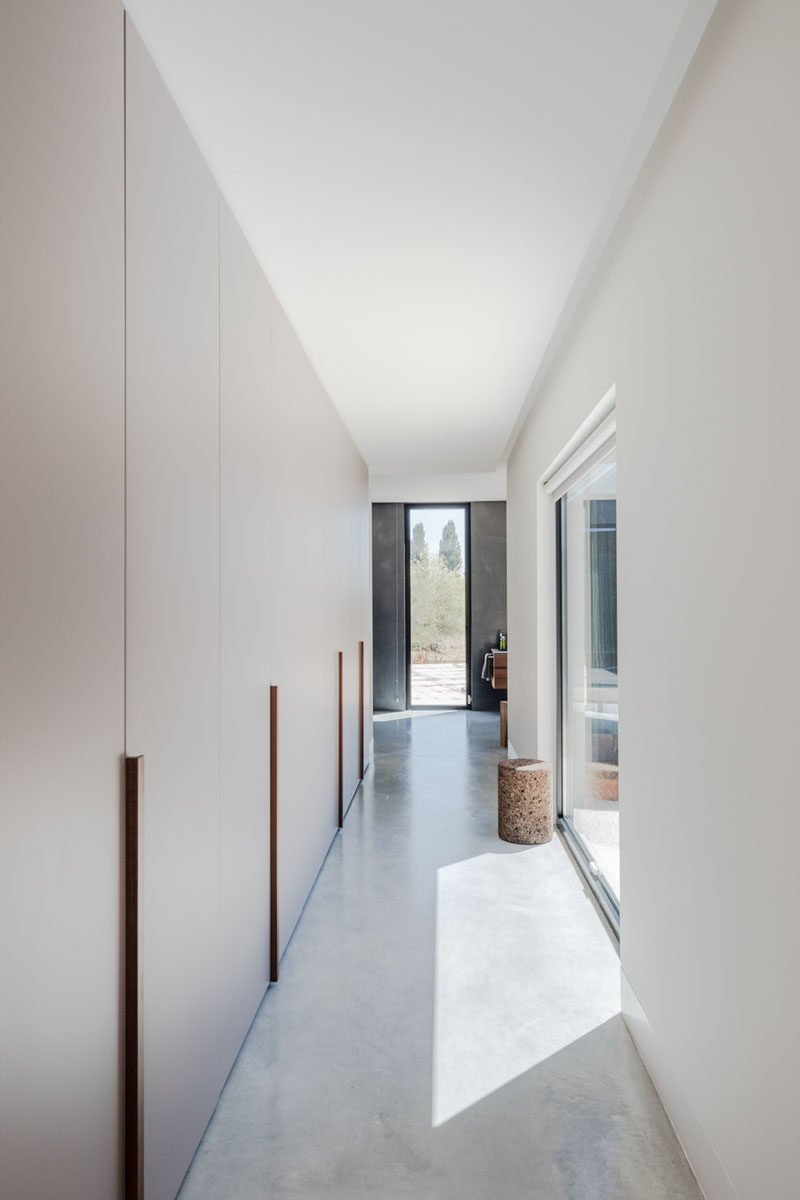 A long row of minimalist cabinets that act as a walk-through closet, connecting the master bedroom with the bathroom. #Closets #Wardrobe #InteriorDesign