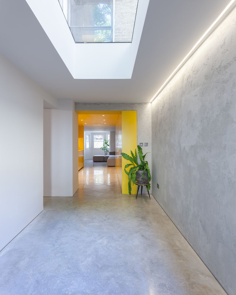 Hidden lighting, a skylight and a yellow kitchen ensure that this modern basement feels bright and open. #Skylight #Lighting #YellowKitchen