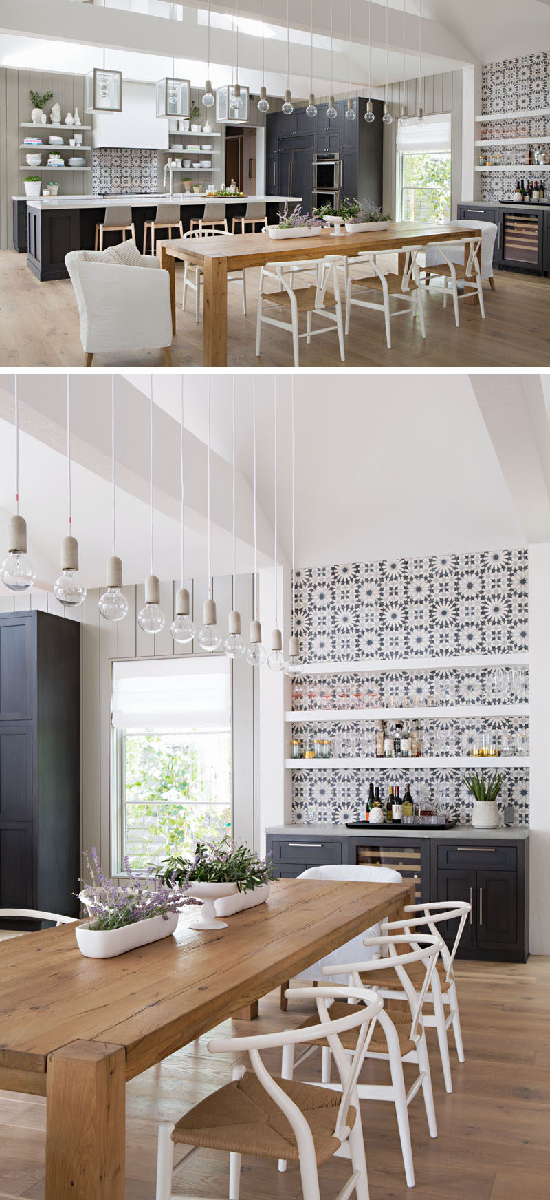 The dining area in this farmhouse inspired house, has a large 8 person wood dining table surrounded by white chairs. Simple light bulbs hang above the dining table, helping to anchor the dining table in the open floor plan, and beside the dining table is a bar area with white floating shelves and decorative tiles. These floating shelves and decorative tiles are also used in the kitchen, creating a cohesive look for the space. #DiningRoom #Kitchen