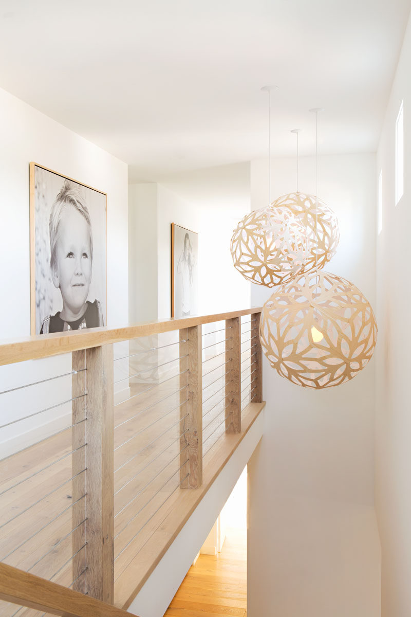 Simple decorative pendant lights hang above the stairs, while a simple wood and wire cable handrail continues with the farmhouse look. #PendantLights #Handrail #InteriorDesign