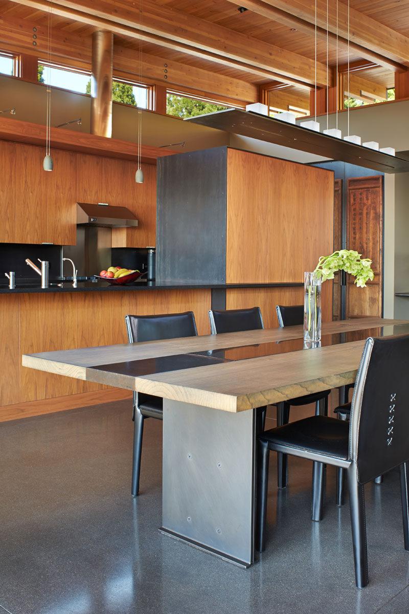 In this contemporary dining room, a custom-designed glass and metal chandelier sits above a custom dining table that's made from wood, steel and concrete. #DiningRoom #DiningTable