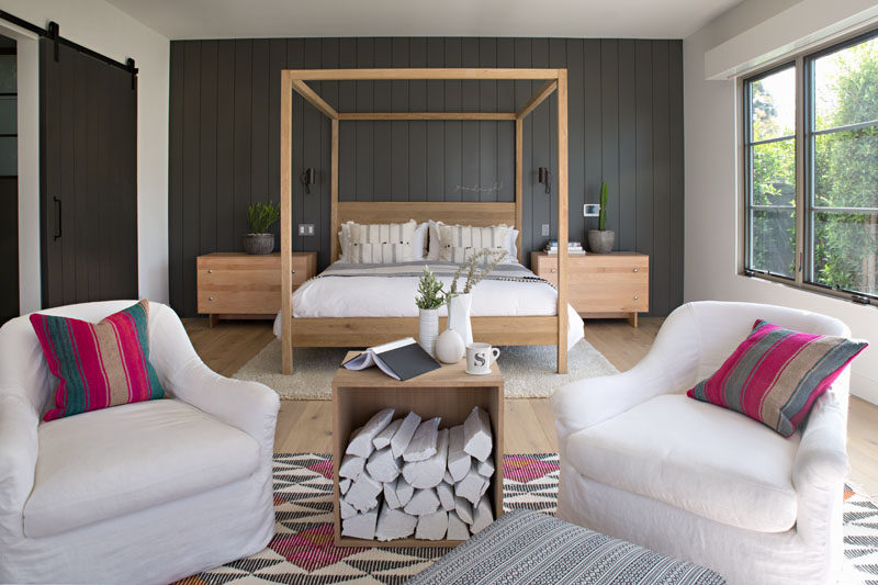 In this farmhouse inspired master bedroom, dark grey wood paneling has been used as an accent wall, while light wood and white furniture help to keep the space bright. #MasterBedroom #GreyAccentWall #BedroomDesign