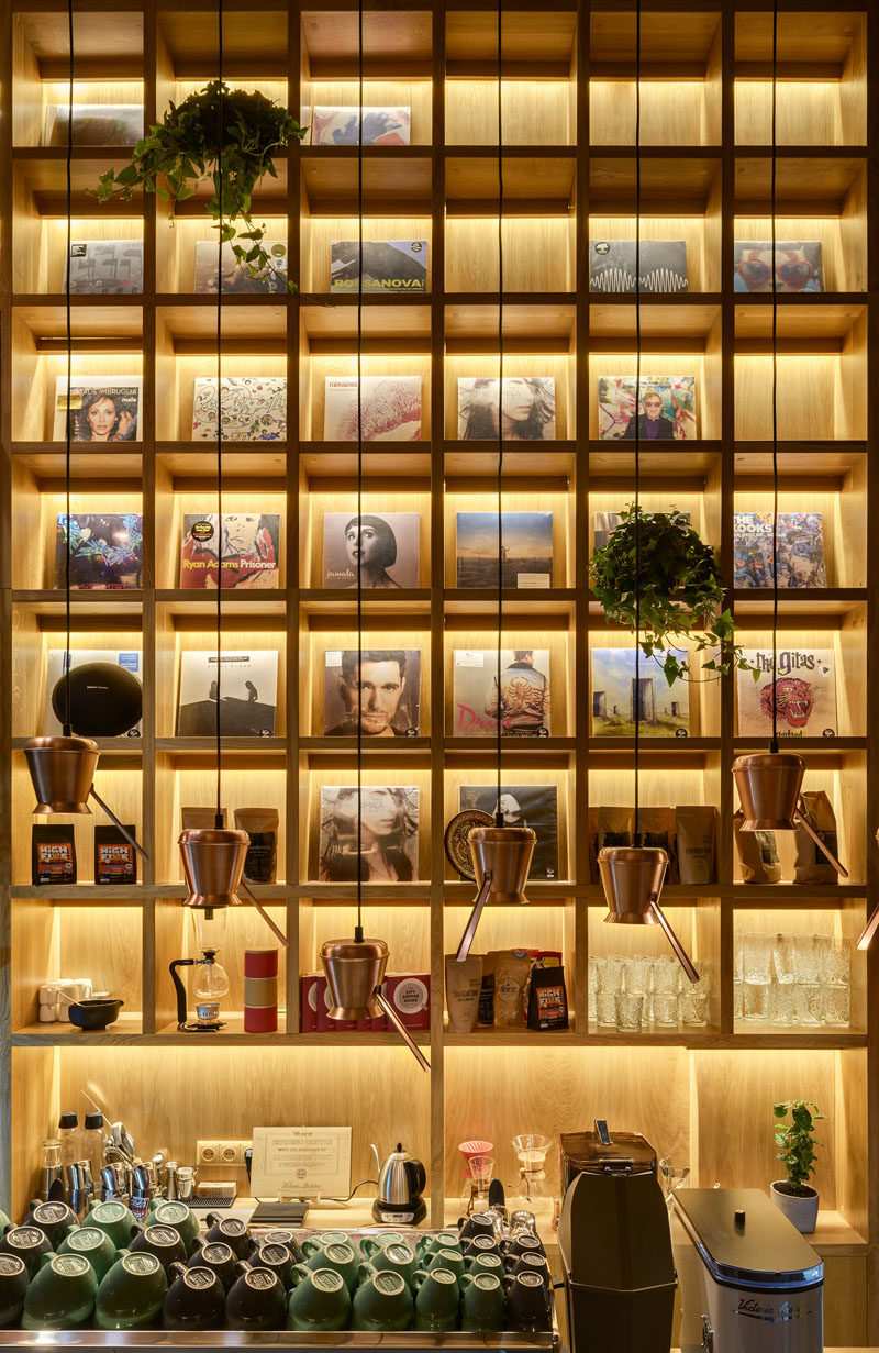 This wood display shelving behind the bar has plenty of space for storage, while backlighting highlights the design and the displayed items, as well as adding light to the interior. #WoodShelving #DisplayShelving #Shelving #CoffeeShop