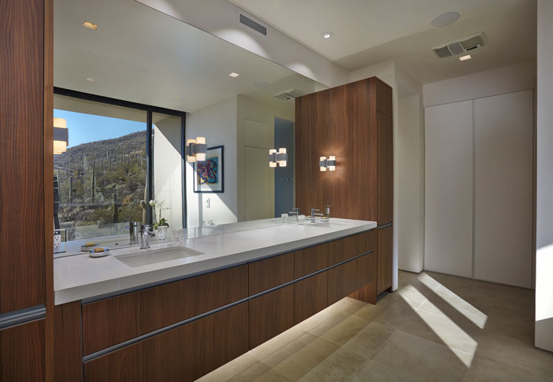 In this modern bathroom there's a large double sink, wood vanity with plenty of storage, and the large mirror reflects the views from outside. #ModernBathroom #LargeVanity #WoodVanity