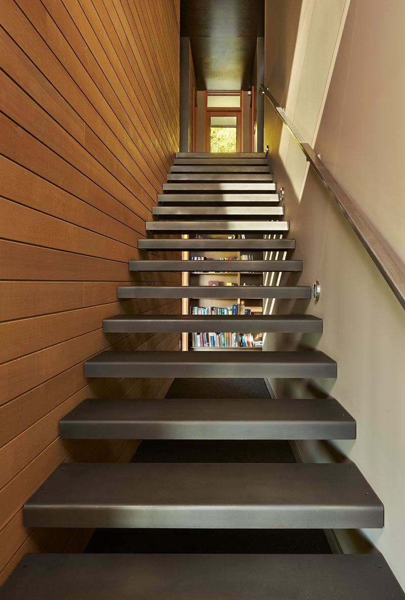 A blackened steel staircase that leads down to the lower floor of this modern house. #SteelStaircase #Steel #Stairs