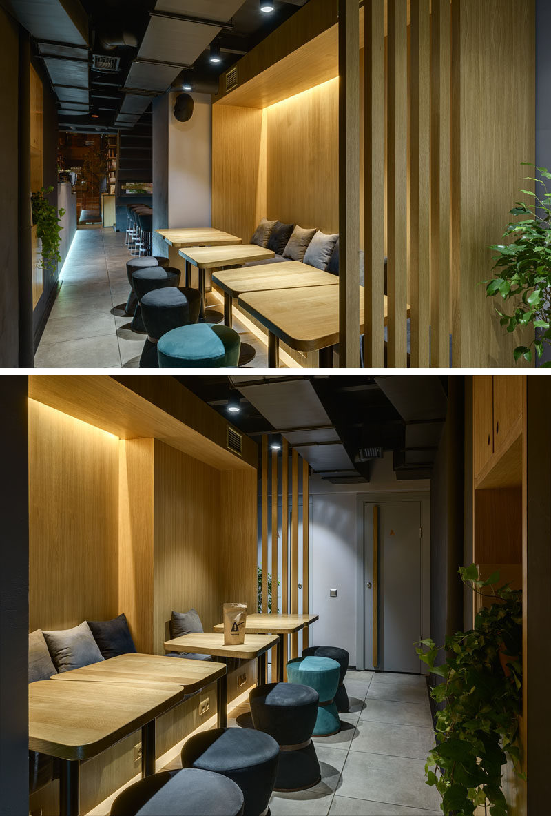 This modern coffee shop seating area is surrounded by wood with banquette seating, wood tables, upholstered stools and hidden lighting. #ModernCoffeeShop #CafeSeating #InteriorDesign