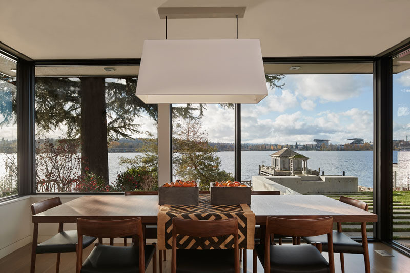 This dining room with a wood table has views of the water through the large picture windows. #DiningRoom #Windows