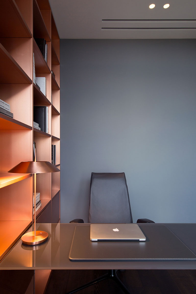 In this modern home office, copper shelving adds a metallic touch to the grey walls. #Copper #GreyWall #HomeOffice