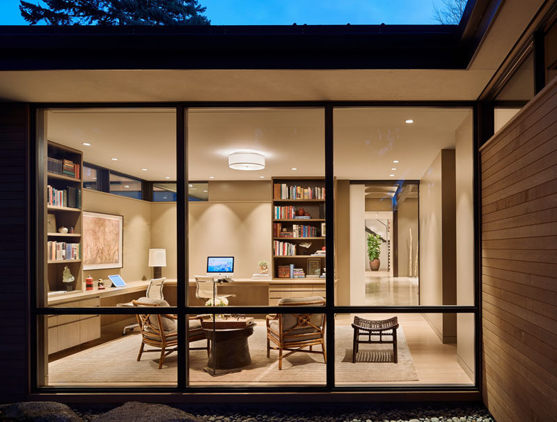 In this contemporary and spacious home office, there's room for two people and a small sitting area. Floor-to-ceiling windows provide natural light and views of the water. #HomeOffice #Windows