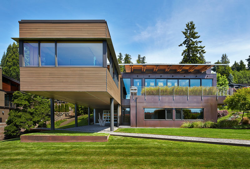 Dark-stained cedar siding and copper panels cover this modern house that has a cantilever and is nestled into a hillside on Mercer Island in Washington. #CedarSiding #CopperPanels #ModernHouse