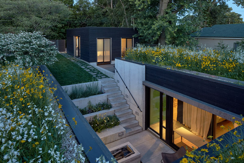 This modern house is sunken down 6 feet from the yard, and a terrace garden leads down to an entry courtyard with a firepit. #Courtyard #Landscaping #GardenDesign #Firepit