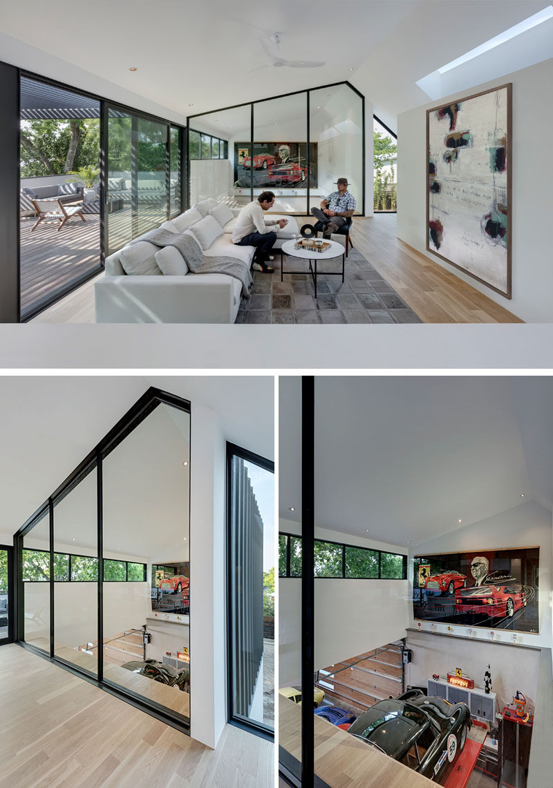 At the top of the stairs in this modern house, there's a large black-framed glass wall that provides a view of the collector cars in the garage below. #InteriorGlassWalls #GlassWalls #Windows