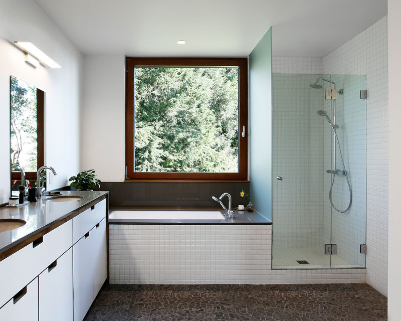 In this modern master bathroom, there's a walk-in shower with a glass surround, and a built-in bathtub that's positioned underneath the window. #MasterBathroom #WalkInShower #BuiltInBathtub