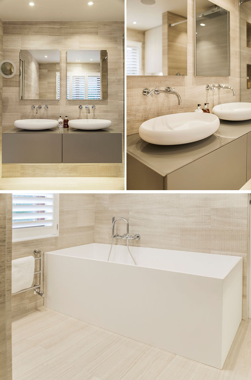 This modern master ensuite bathroom features a natural and luxurious appearance, with light and natural colors, while touches of white draw attention to the curved sinks and the rectangular bathtub. #MasterBathroom #BathroomDesign