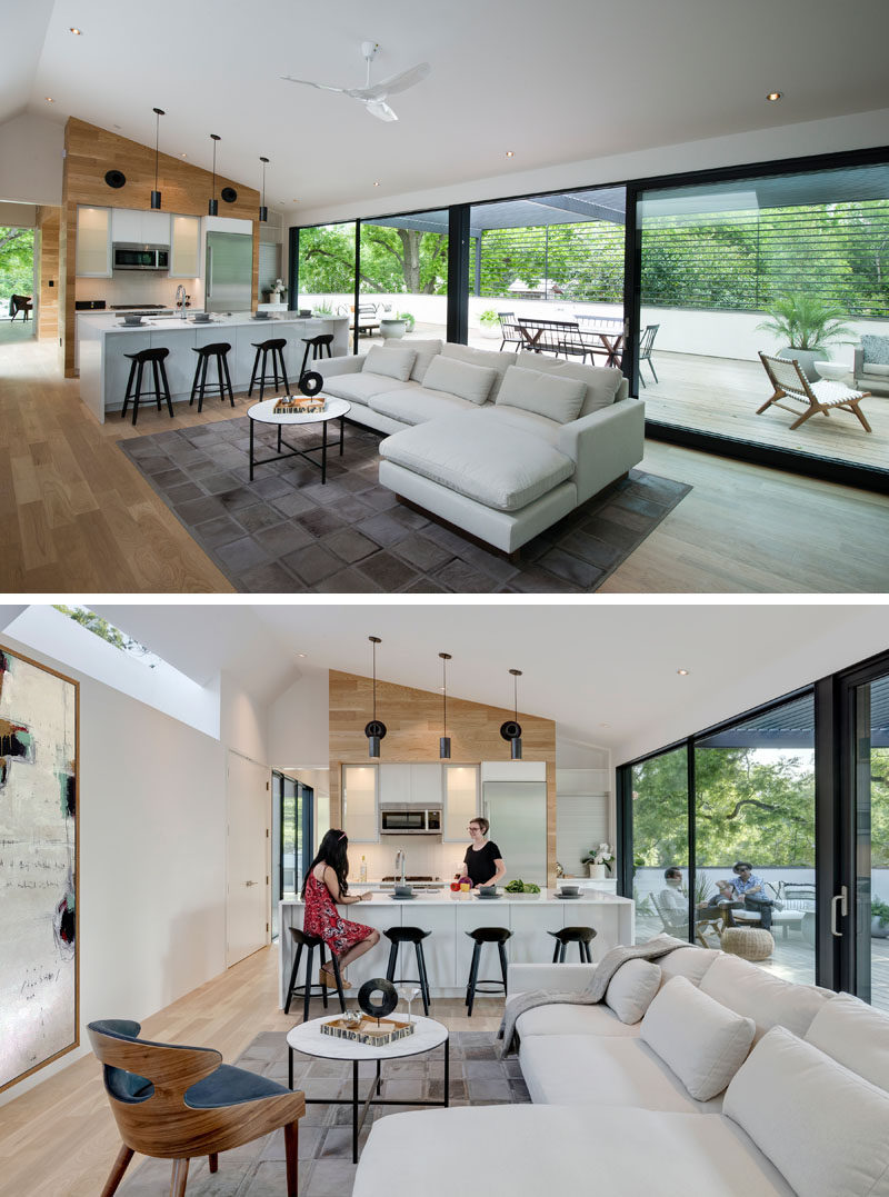 The main living area of this modern house is open plan, with the living room and kitchen sharing the same space. A wood accent wall and wood flooring helps to warm up the mostly white interior. #ModernInteriorDesign #LivingRoom #KitchenDesign