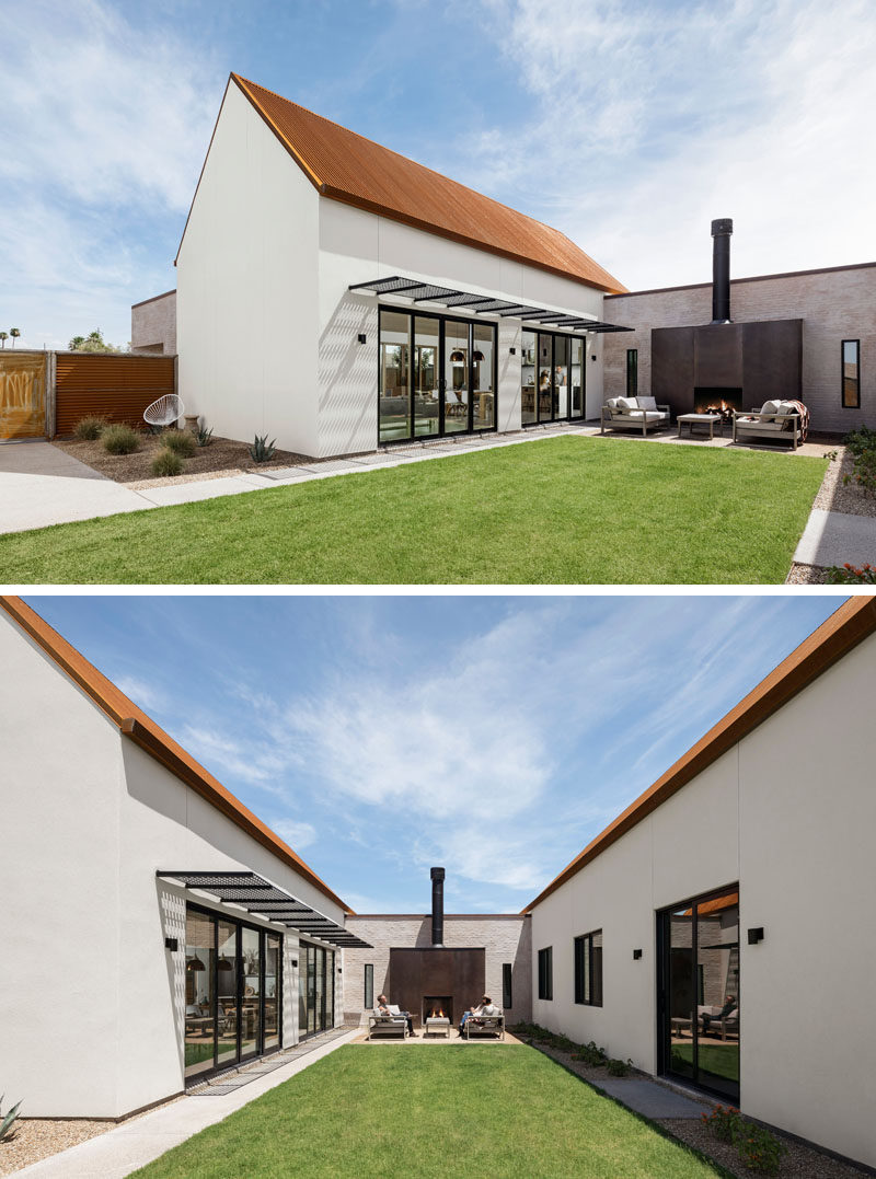 This modern house opens up to a central courtyard with an outdoor lounge area anchored by a rusted steel clad outdoor fireplace and a grassy lawn area. #OutdoorFireplace #Landscaping #ModernHouse