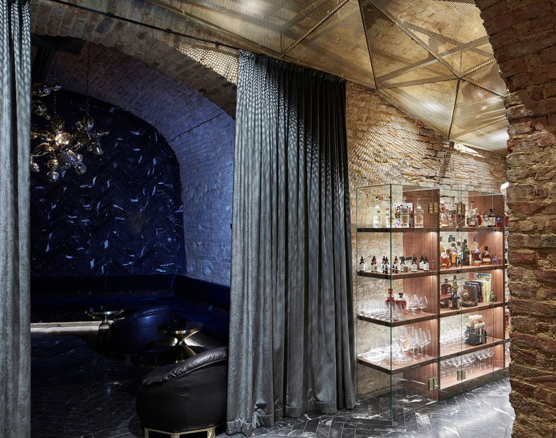 In this underground bar, there are numerous alcoves have a variety of seating options for guests. In this alcove, there's a darkened room with dark leather couches hidden by curtains. #UndergroundBar #BarDesign #InteriorDesign