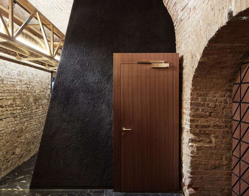 Wood doors with gold hardware compliment the wood stairs and the gold clad ventilation pipes in this underground bar. #UndergroundBar #Doors