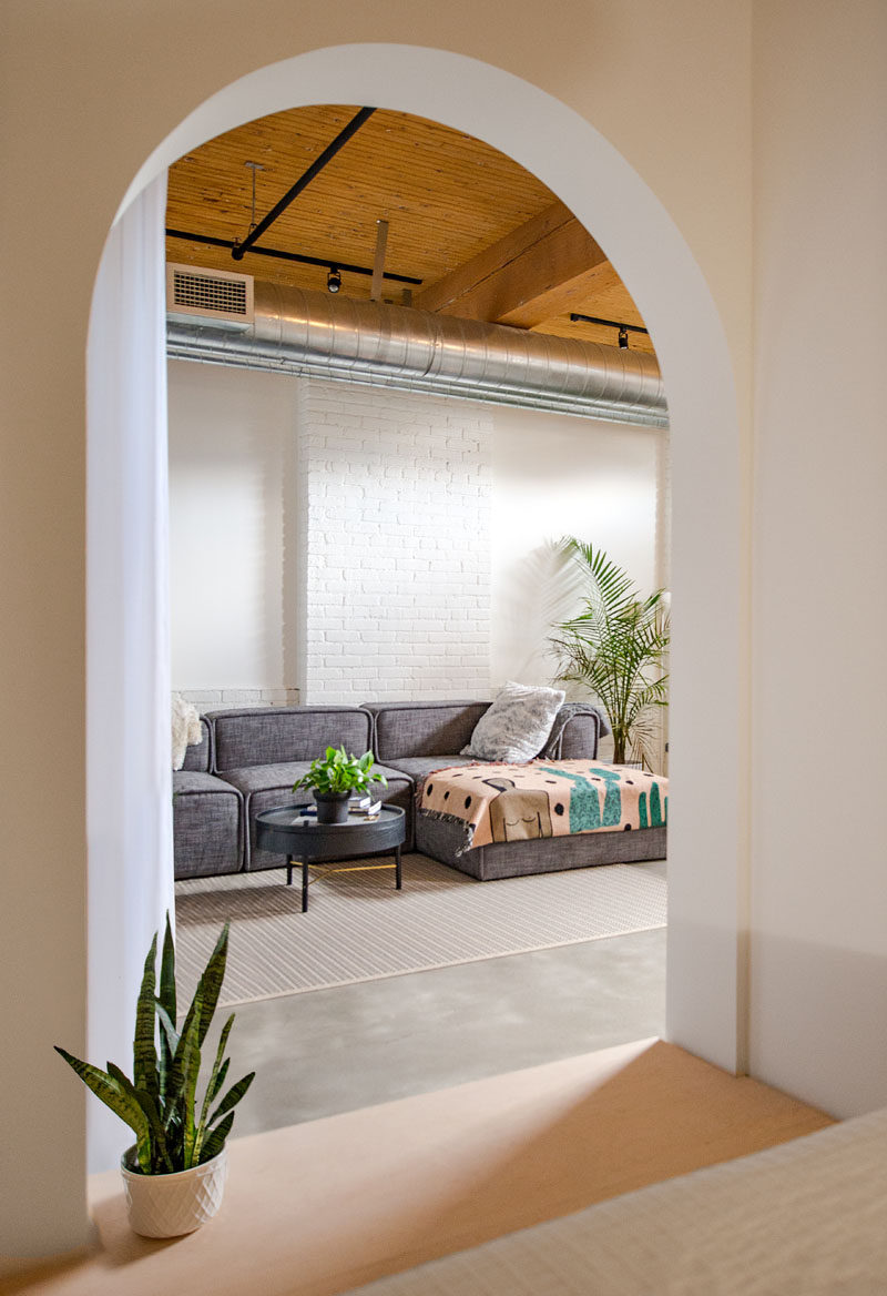 This modern loft has a living room that's been set up with a low couch, rug and a couple of plants.