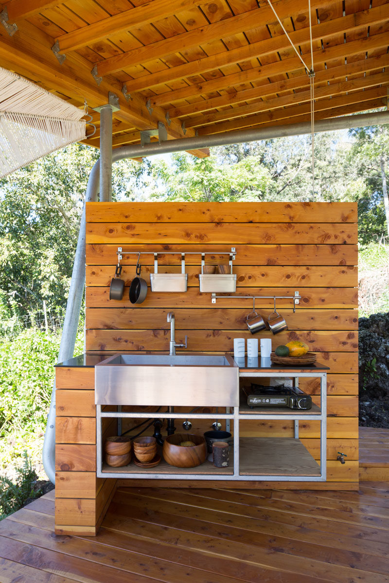 The outdoor pavilion also has a kitchen with a stainless steel shelving unit and sink. #OutdoorKitchen