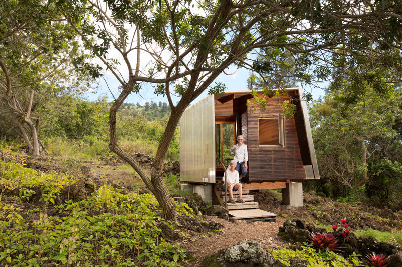 This small and modern cabin houses a small bedroom that looks out towards the lava flow through a large sliding window. Inside, the walls are covered in wood and there's just enough room for a bed, a built-in bench and a small desk with chair. #ModernCabin #Architecture