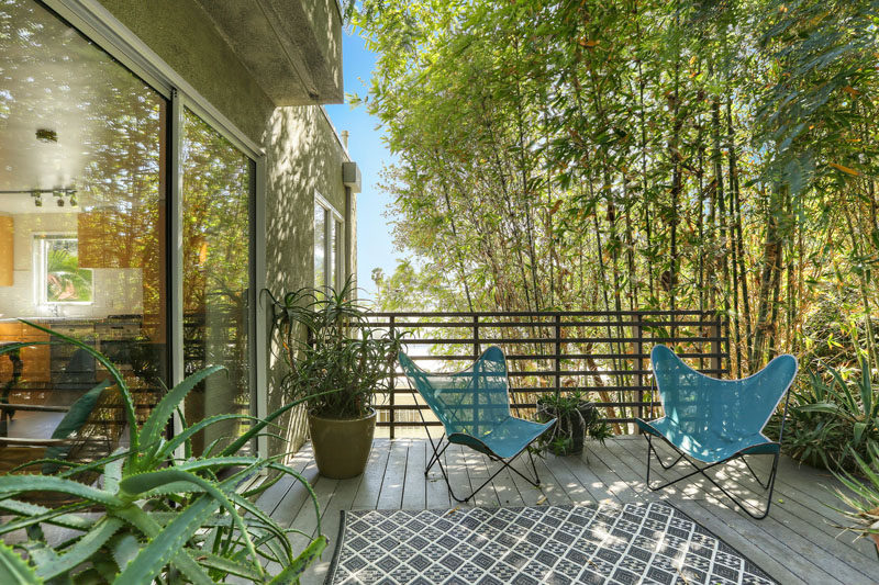 This private deck that's set up with planters and chairs, has views of the surrounding tall trees. #PrivateDeck #OutdoorSpace