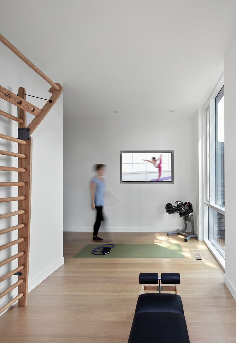 This modern house has an area that's dedicated to a small gym with space for a yoga mat to be positioned in front of a window. #HomeGym #Gym