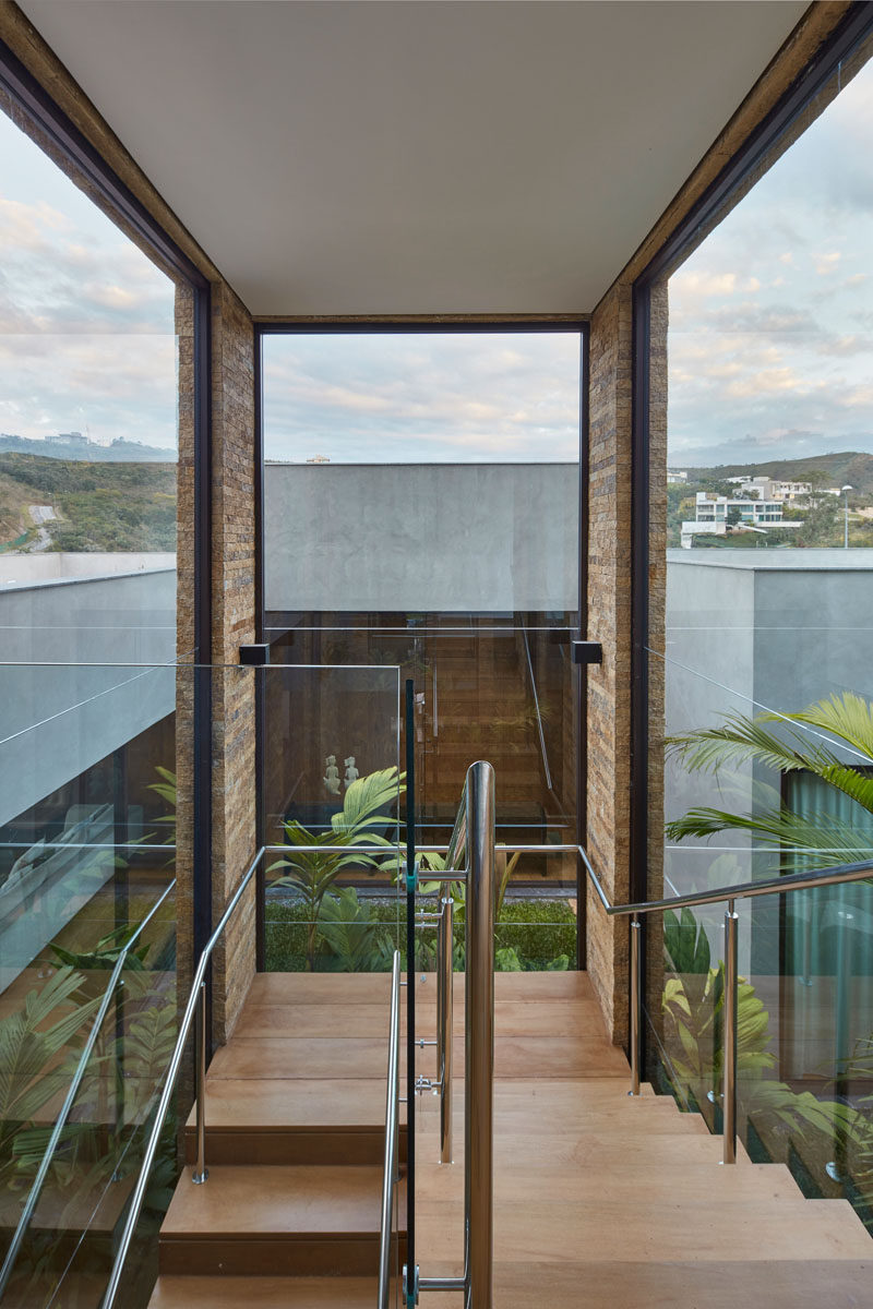 These wood stairs that lead to the second floor of this modern house are constructed over an internal garden, while large windows provide views of the surrounding landscape. #Stairs #Windows #ModernHouse