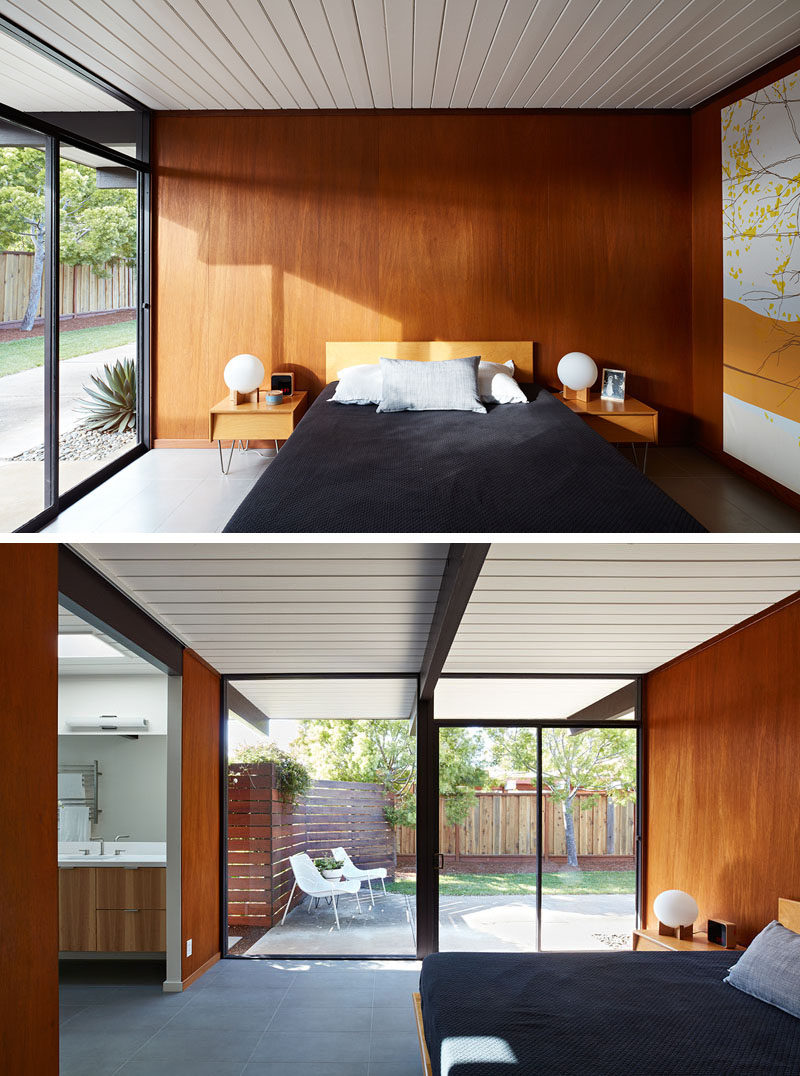 In this mid-century modern bedroom, the white wood ceiling runs from the interior through to the exterior of the house, while sliding glass doors provide the bedroom with access to a small patio. #Bedroom #BedroomDesign #WoodWall