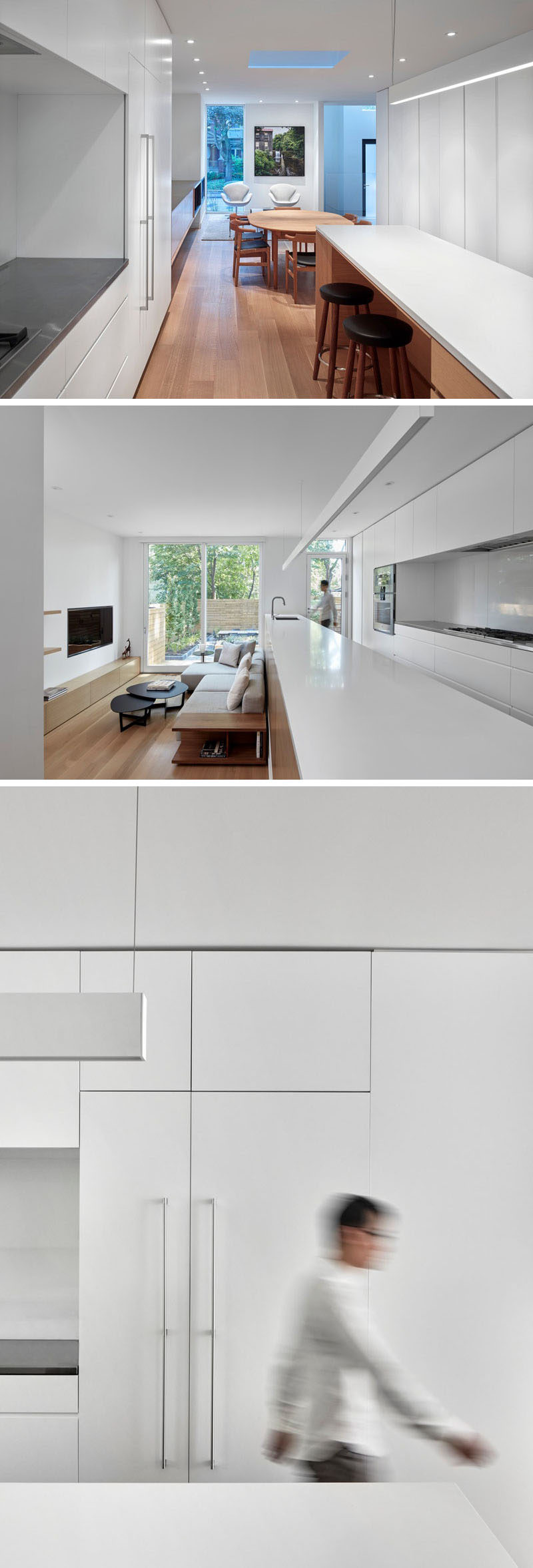 White minimalist cabinets fill the wall, and a long kitchen island with space for seating provides a backdrop for the living room that's stepped down from the kitchen. #WhiteKitchen #MinimalistKitchen #LivingRoom