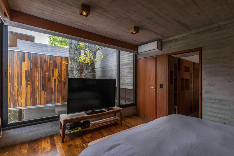 In this modern bedroom, large windows allow the sunlight to brighten up the room and show off the established trees. #ModernBedroom #Windows