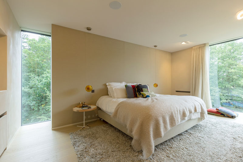 In this modern bedroom, a partial wall provides a place to anchor the bed in the room, while a large rug, light curtains and a big blanket create a cozy atmosphere. #Bedroom #InteriorDesign