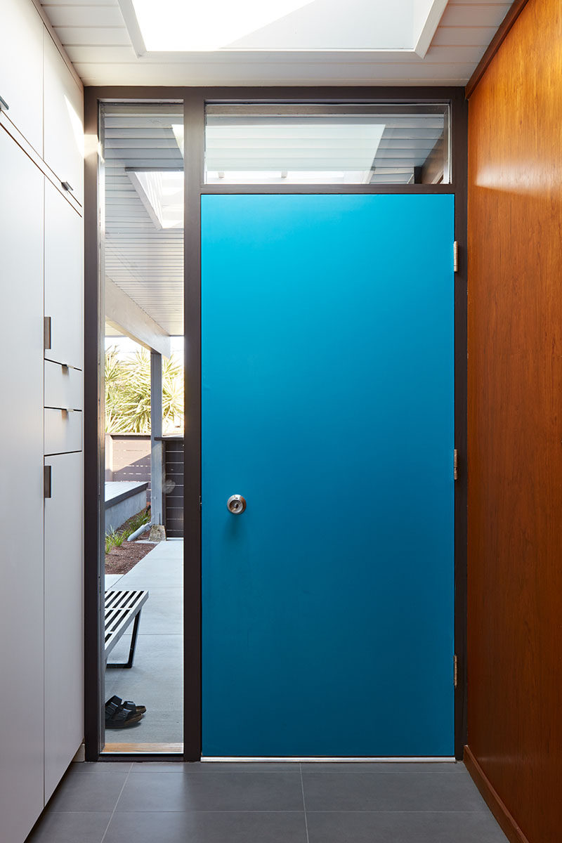 This renovated entryway with a bright blue front door, was expanded to create new storage, while still retaining some of the original wood walls. #EntryWay #BlueFrontDoor