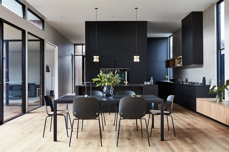 Matte black furniture in the dining room complements the matte black kitchen in this modern house. #MatteBlack #DiningRoom #Kitchen