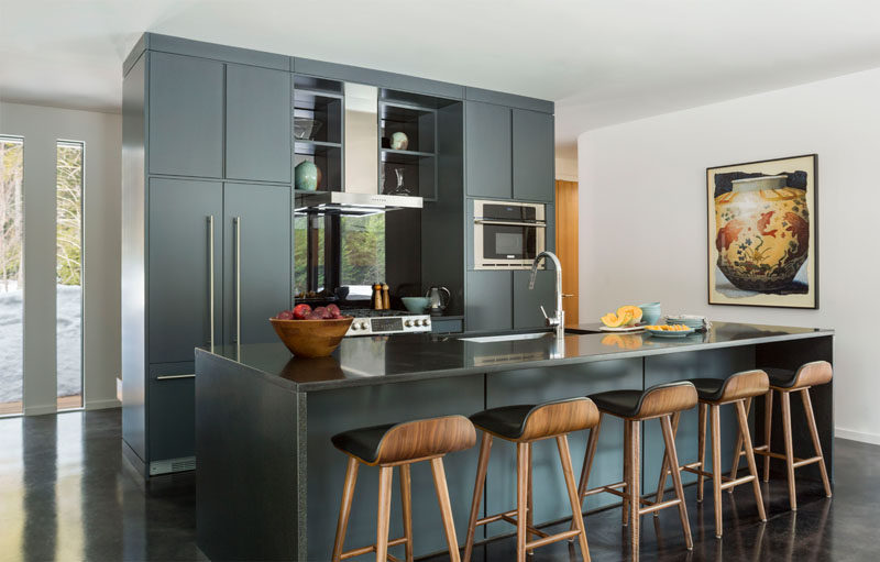 In this modern kitchen, minimalist grey cabinets are combined with stainless steel appliances and a large island with plenty of room for seating. #ModernKitchen #GreyKitchen #KitchenDesign