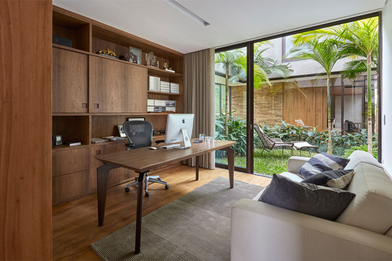 This modern home office with built-in wood shelving has access to an internal garden. #InternalGarden #HomeOffice #WoodShelving