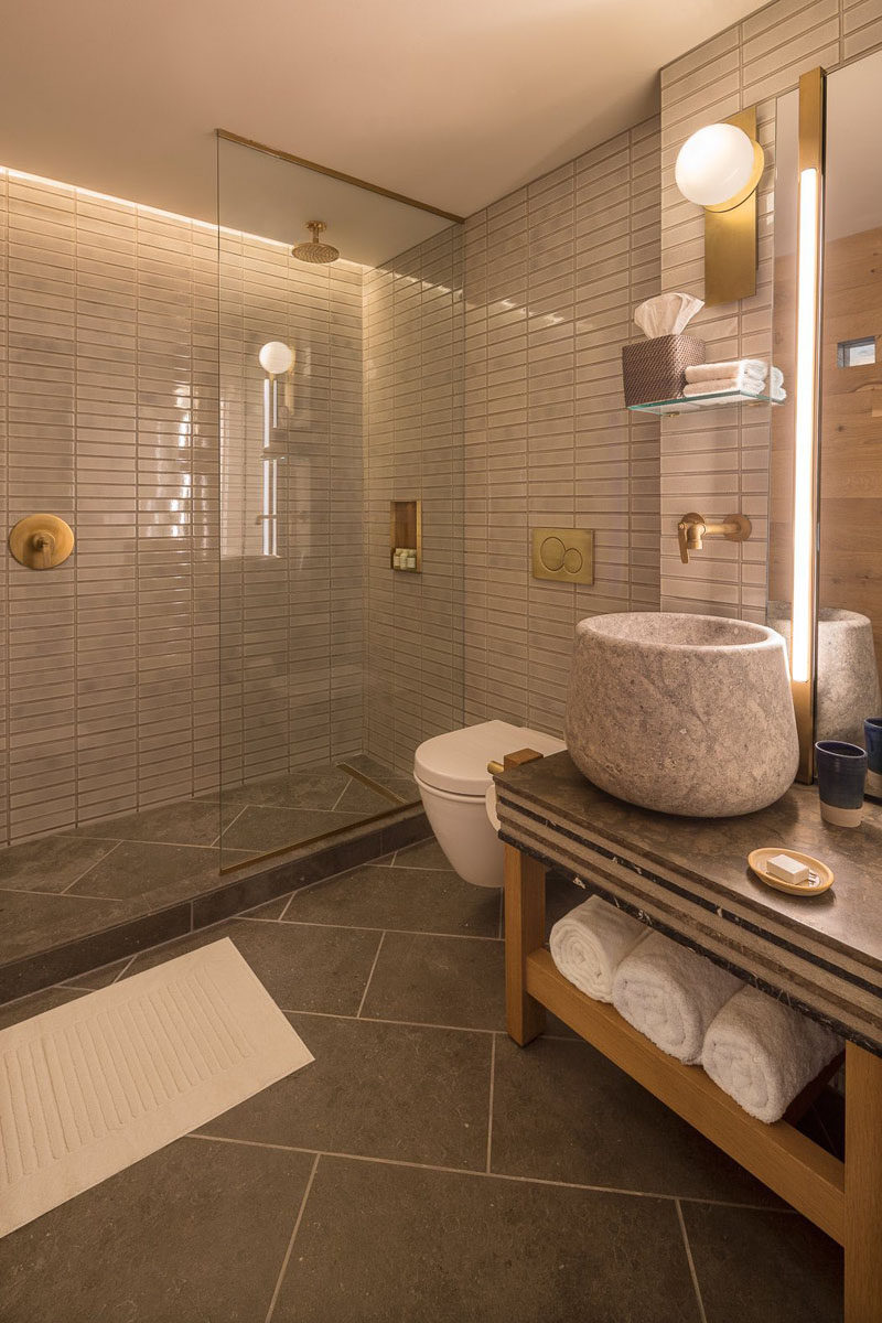 In this modern hotel bathroom, tiles cover the walls while in the shower, hidden lighting creates a soft glow. #ModernBathroom #BathroomDesign