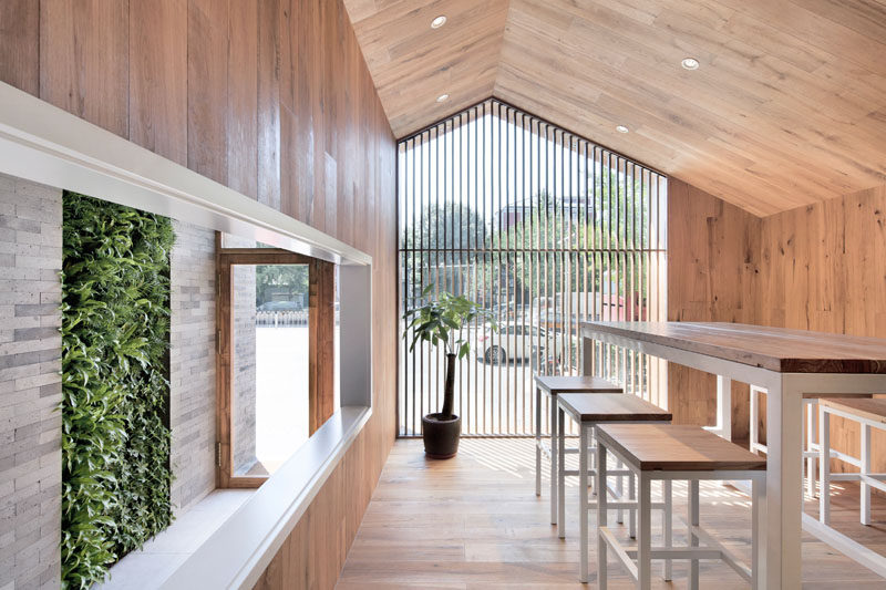 Upon entering this modern hotel, the bricks and wood flow through to the interior and there's a small green wall to add a touch of natural color. #ModernHotel #GreenWall #WoodRoom